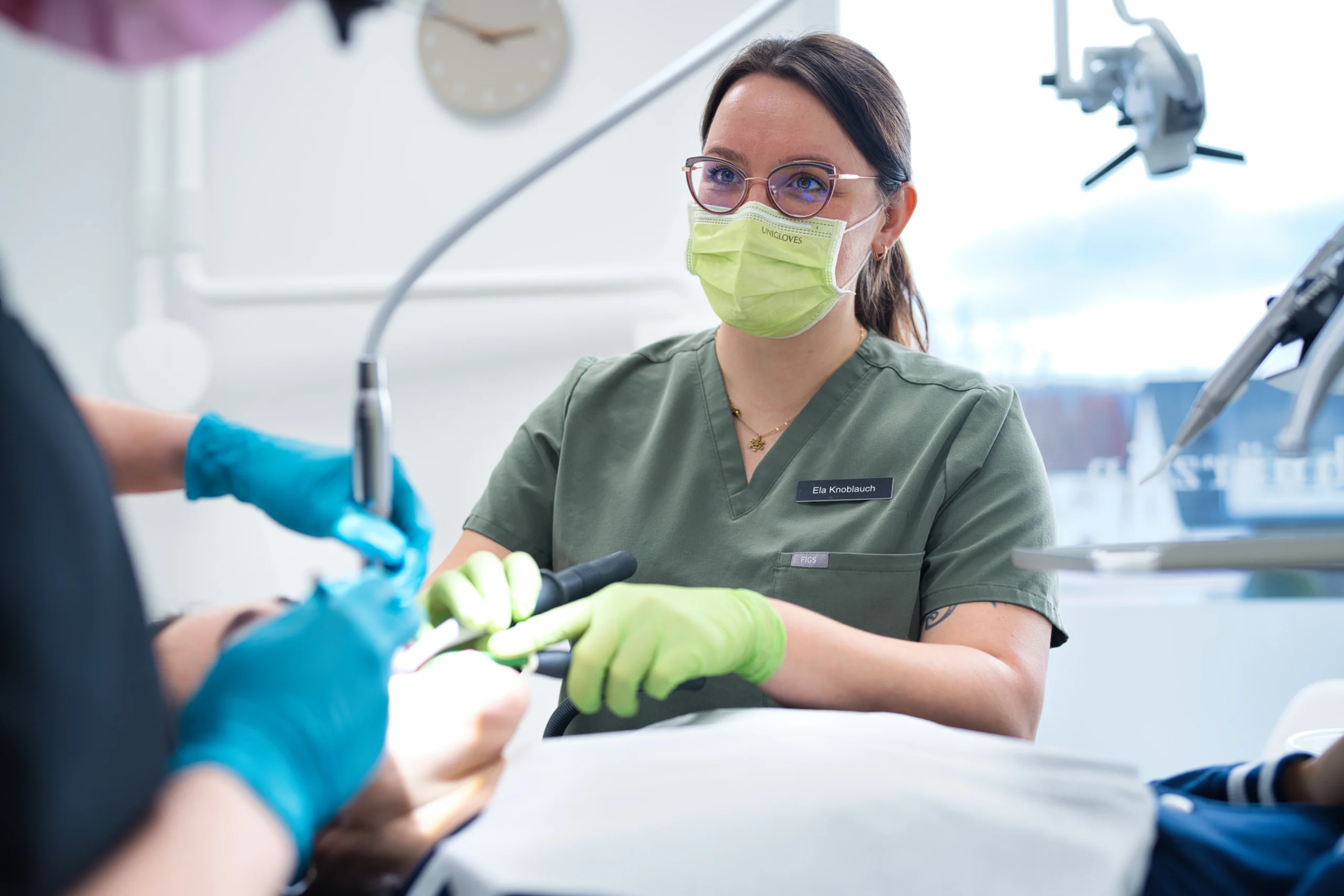 Eine Mitarbeiterin untersucht die Zähne einer Patientin im Behandlungsstuhl.