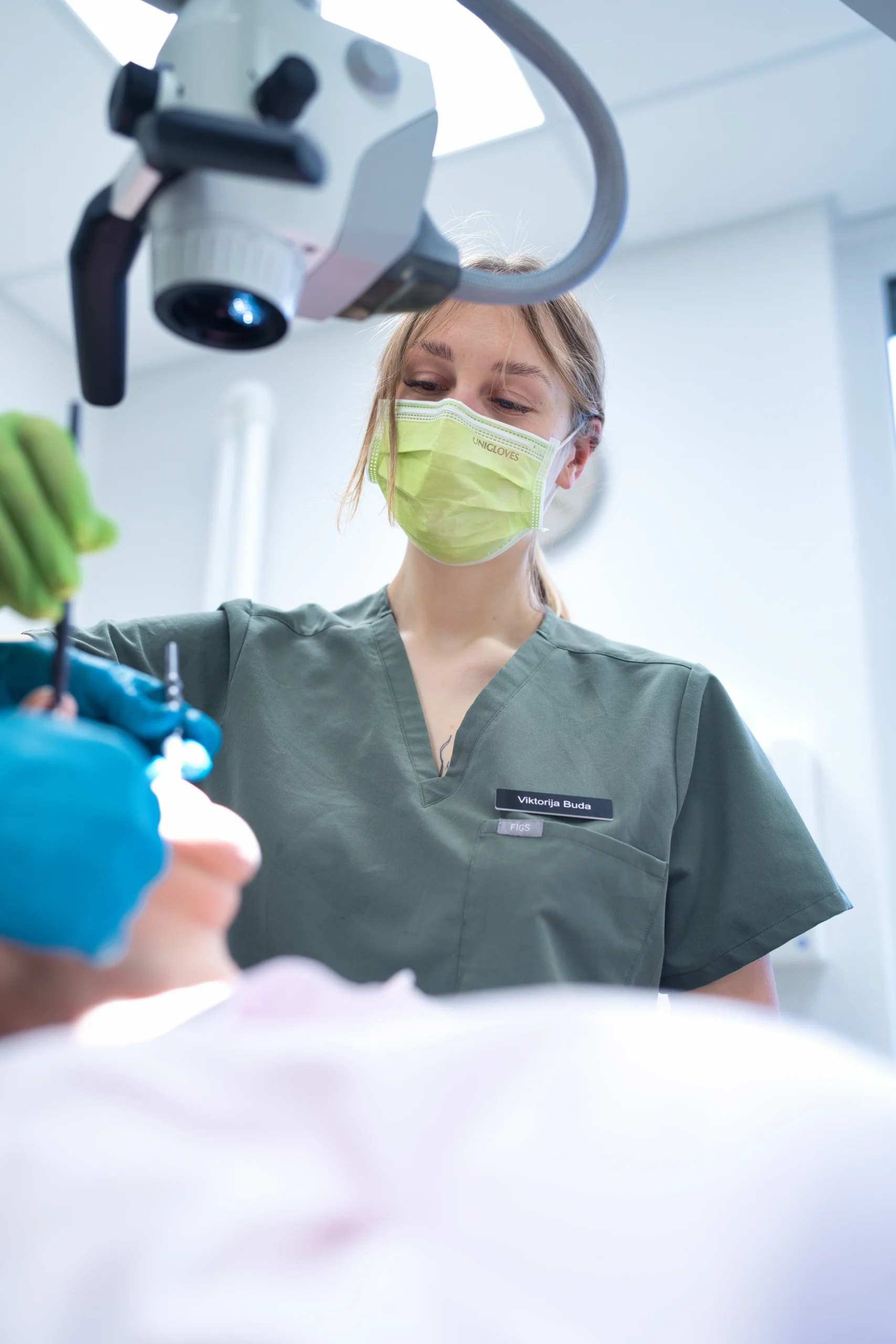 Eine Mitarbeiterin arbeitet mit dem Dentalmikroskop während einer Zahnbehandlung.