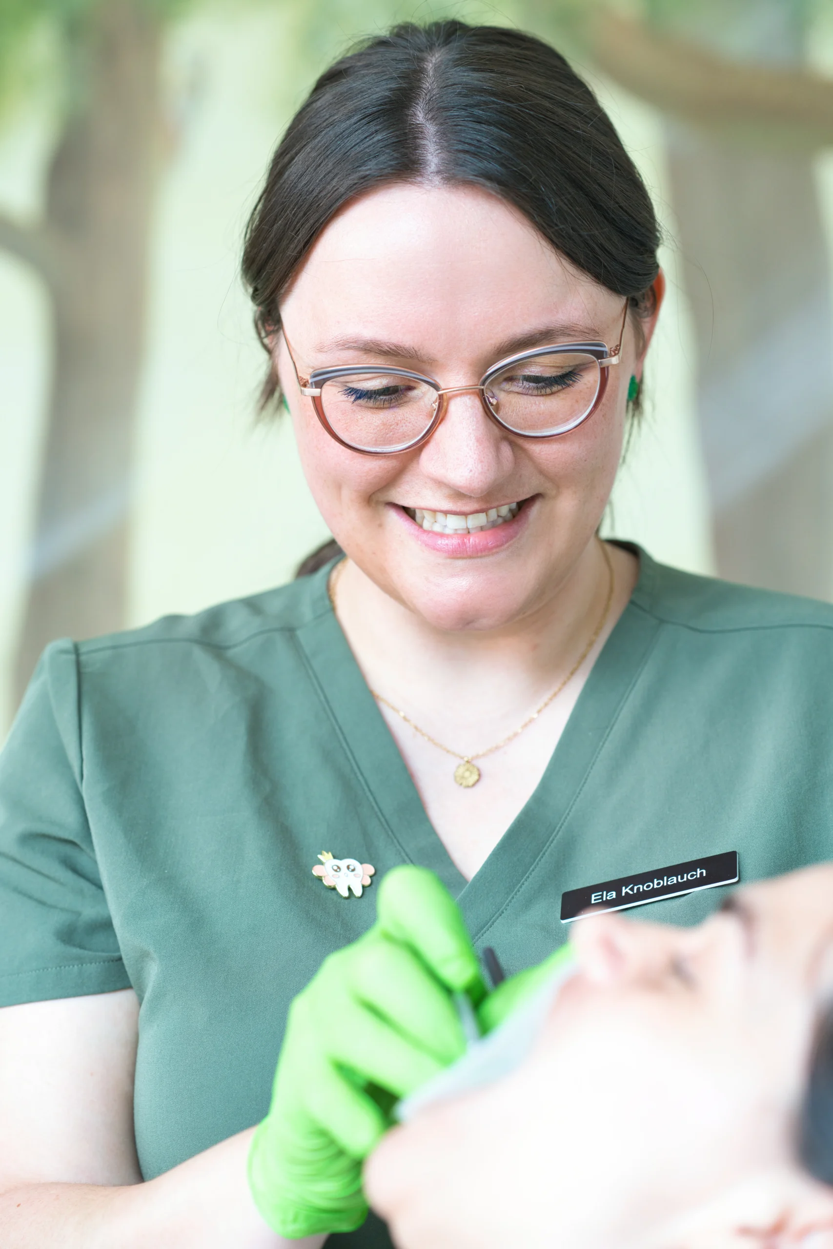 Eine Mitarbeiterin lächelt eine Patientin im Behandlungsstuhl an.