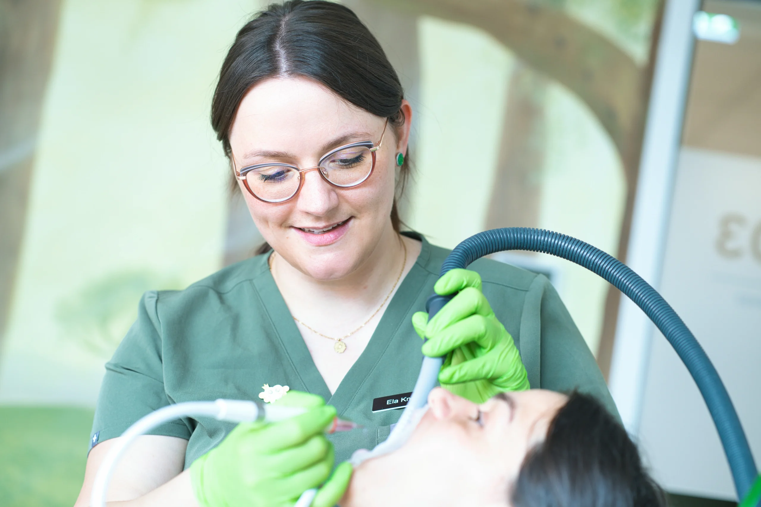 Eine Mitarbeiterin untersucht die Zähne einer Patientin.