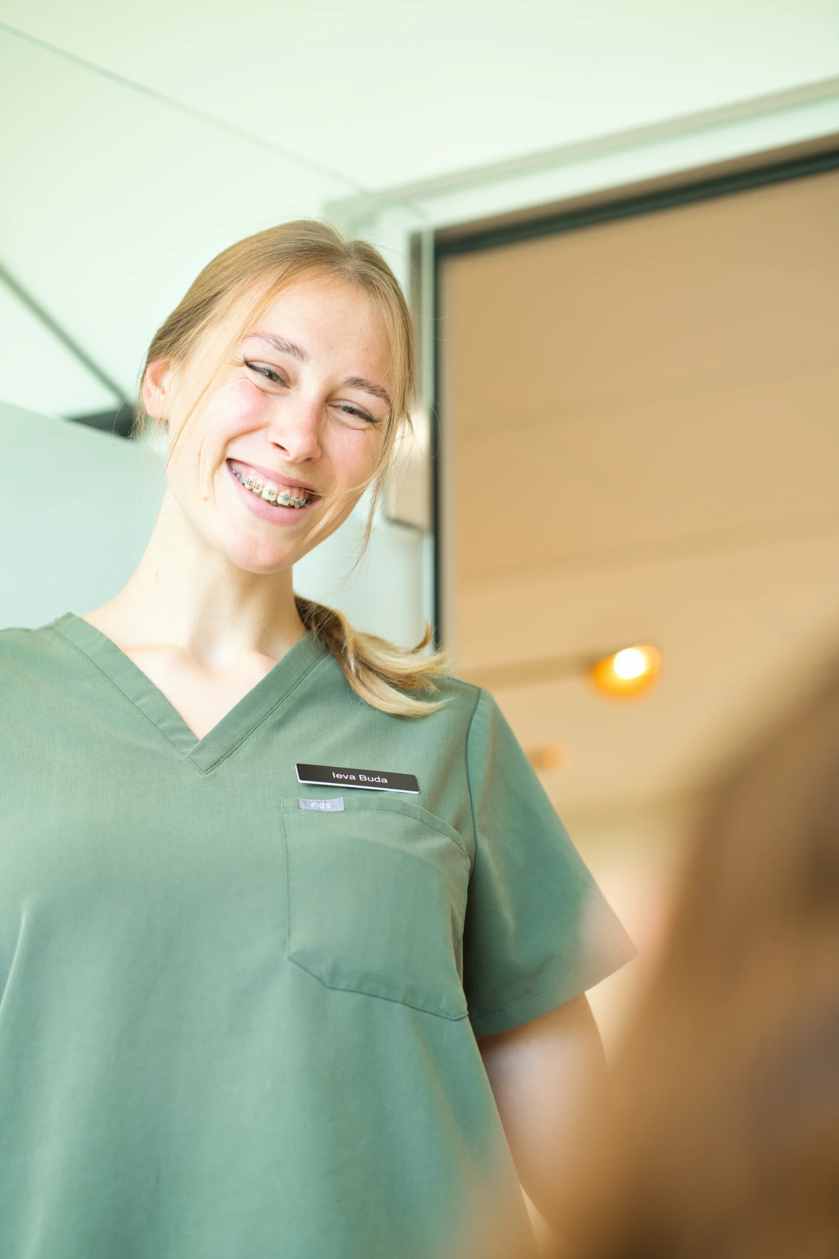 Eine Mitarbeiterin spricht lächelnd mit einer Patientin im Behandlungsstuhl.
