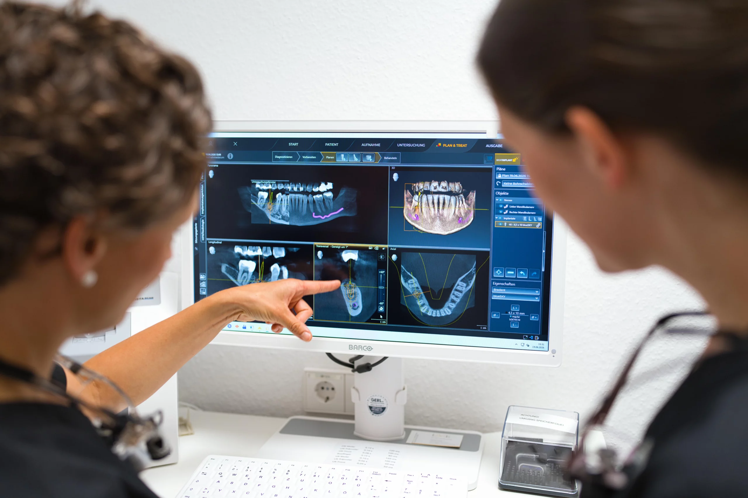 Dr. Lea von Einsiedel erläutert einer Mitarbeiterin Informationen am Diagnosemonitor.