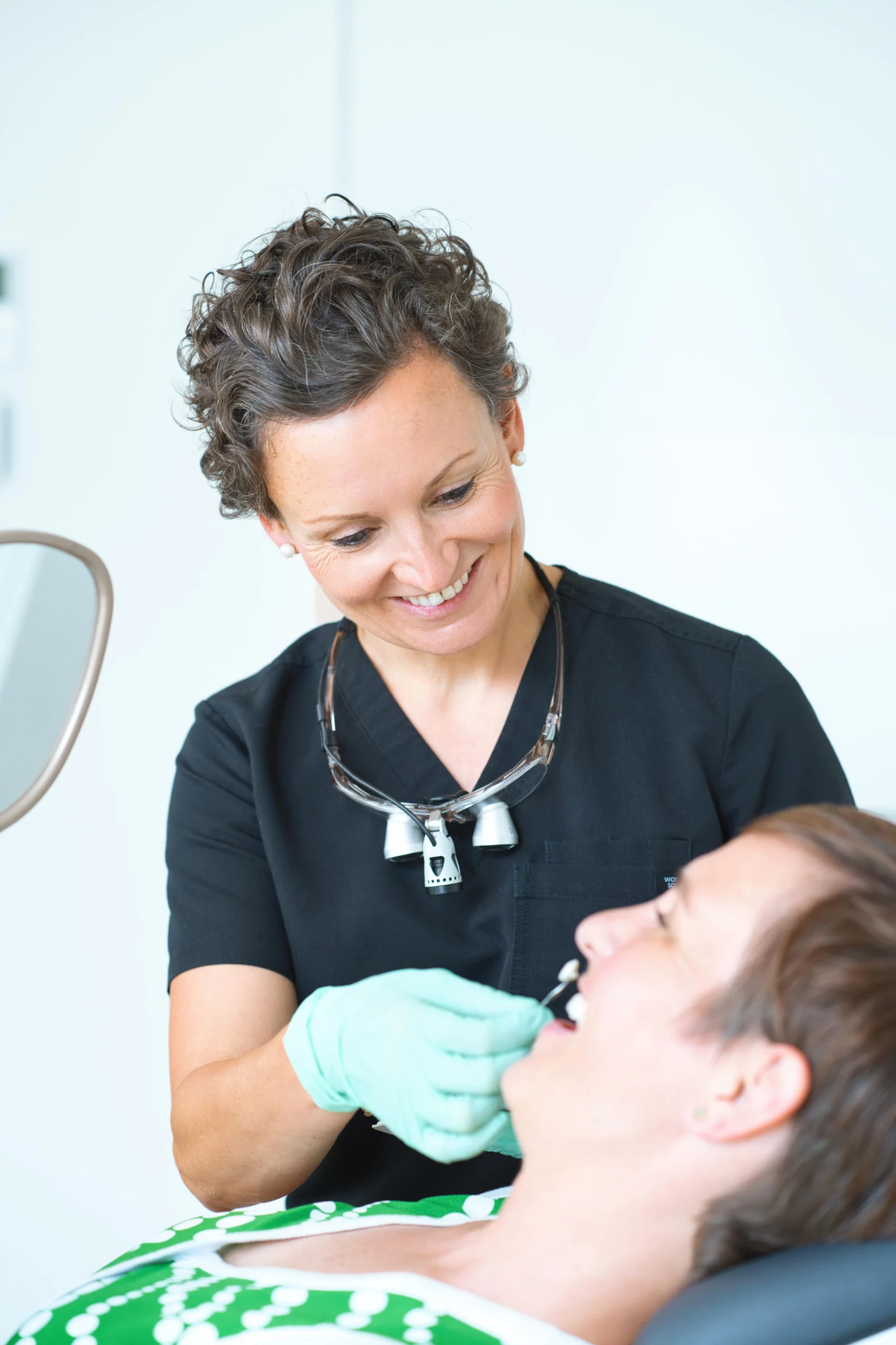 Dr. Lea von Einsiedel untersucht die Zähne einer Patientin mit einem Instrument.